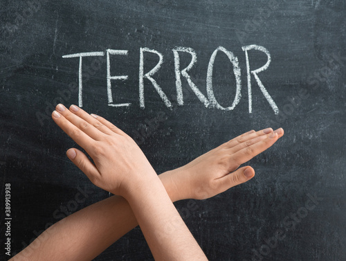 The inscription TERROR on a chalkboard, crossed female hands on the background of the text