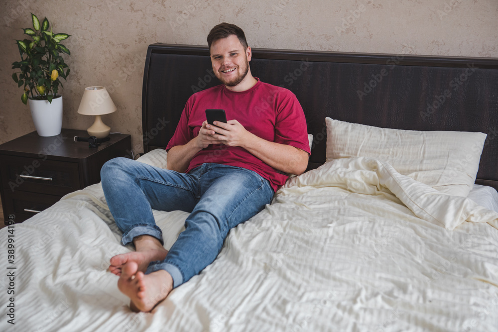 man sitting in bed surfing internet on the phone