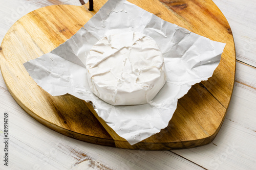 Round piece of camembert cheese on a wooden background.
