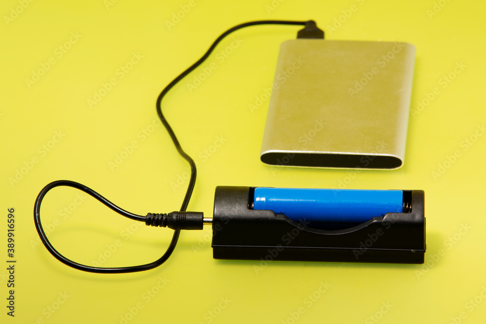 Battery Charger with battery size AA rechargeable with Charger Plug in power outlet adapter in yellow Isolated Background Battery Charger with battery size AA rechargeable with Charger Plug in power outlet adapter in yellow Isolated Background
