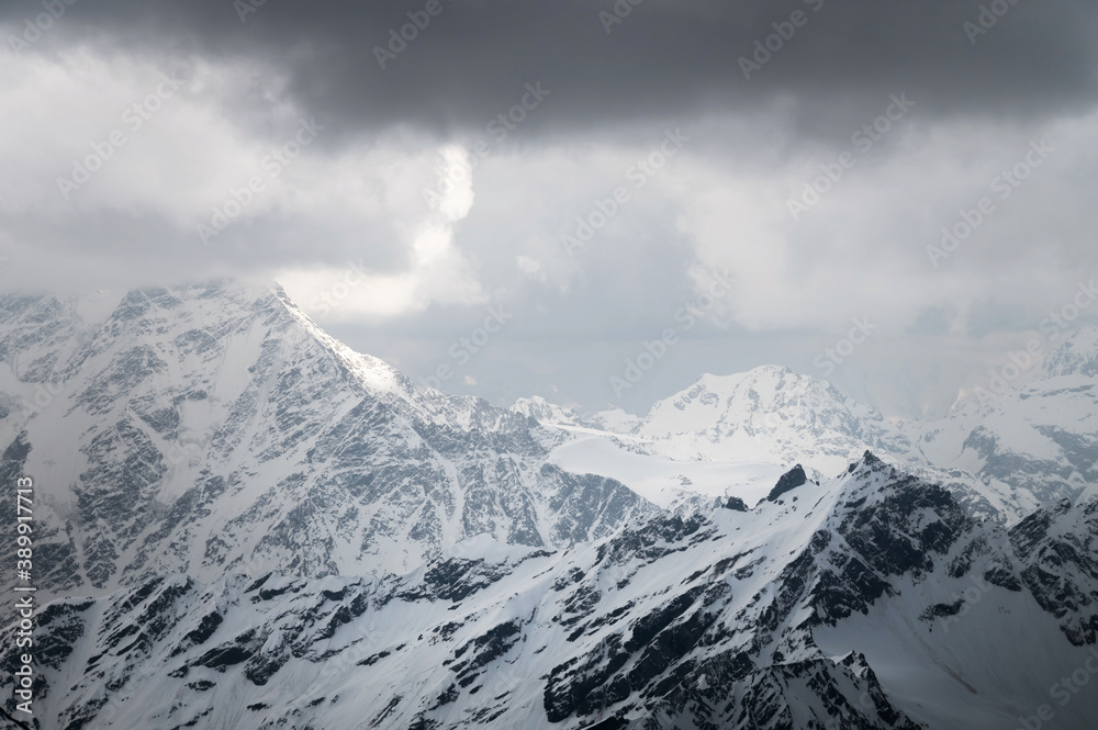 Snow-capped peaks of the Caucasian high mountains in the evening. Dramatic sky