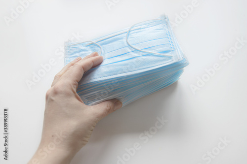 Hand holding a pack of medical masks close-up. Medical disposable masks isolated on a white background with a copy of the space. The concept COVID-19.