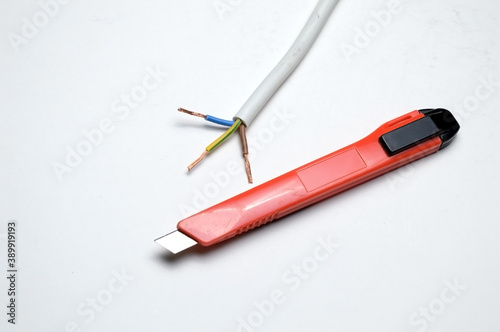 stripped three-wire, electric cable and stationery knife. on white background.