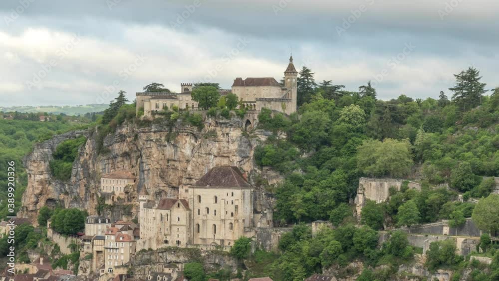 Clouds zoom across the sky above Rocamadour, France with stone architecture and old monastery high on cliff over the village. Scenic beauty and quaint village of France. Time lapse view. Clouds zoom across the sky above Rocamadour, France with stone architecture and old monastery high on cliff over the village. Scenic beauty and quaint village of France. Time lapse view.