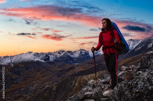 Woman Standing on Rocks looking at Scenic Mountain Peaks and Valley, Fall in Canadian Nature. Dramatic Twilight Sky Adventure Composite. Bacground Landscape. Tombstone Territorial Park, Yukon, Canada. © edb3_16