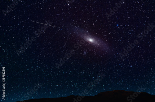 Beautiful Andromeda galaxy  on the starry sky over the hill silhouette. Night photography Astronomical wallpaper.
