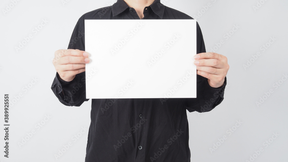 Male asian wear black shirt and hand is holding blank A4 paper on white background.Empty space for text. Male asian wear black shirt and hand is holding blank A4 paper on white background.Empty space for text.