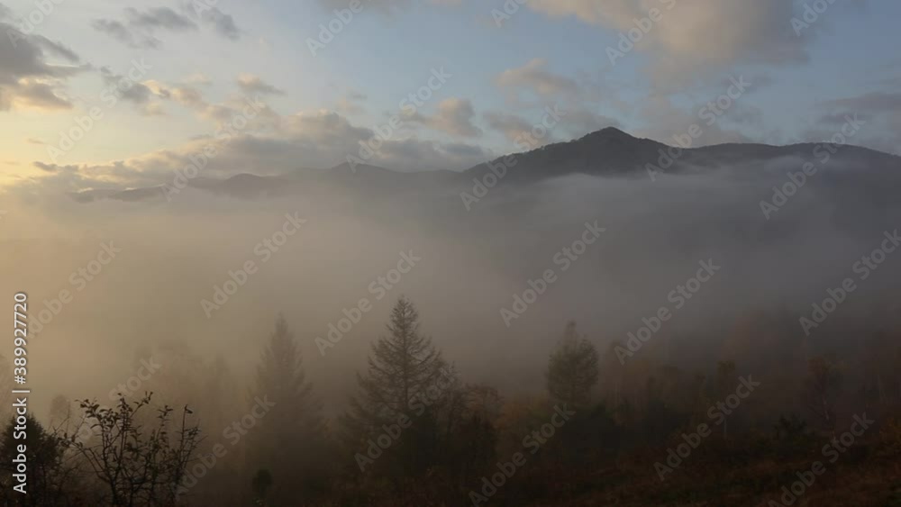 Magical scenic mountain landscape at sunrise. The mountain river is covered with morning fog in the first rays on a background of mountains. Autumn fog over the mountain river Stryi at sunrise. Magical scenic mountain landscape at sunrise. The mountain river is covered with morning fog in the first rays on a background of mountains. Autumn fog over the mountain river Stryi at sunrise.