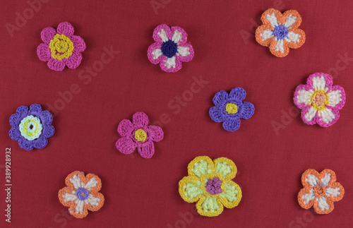 Multicolored crocheted flowers on a red background.