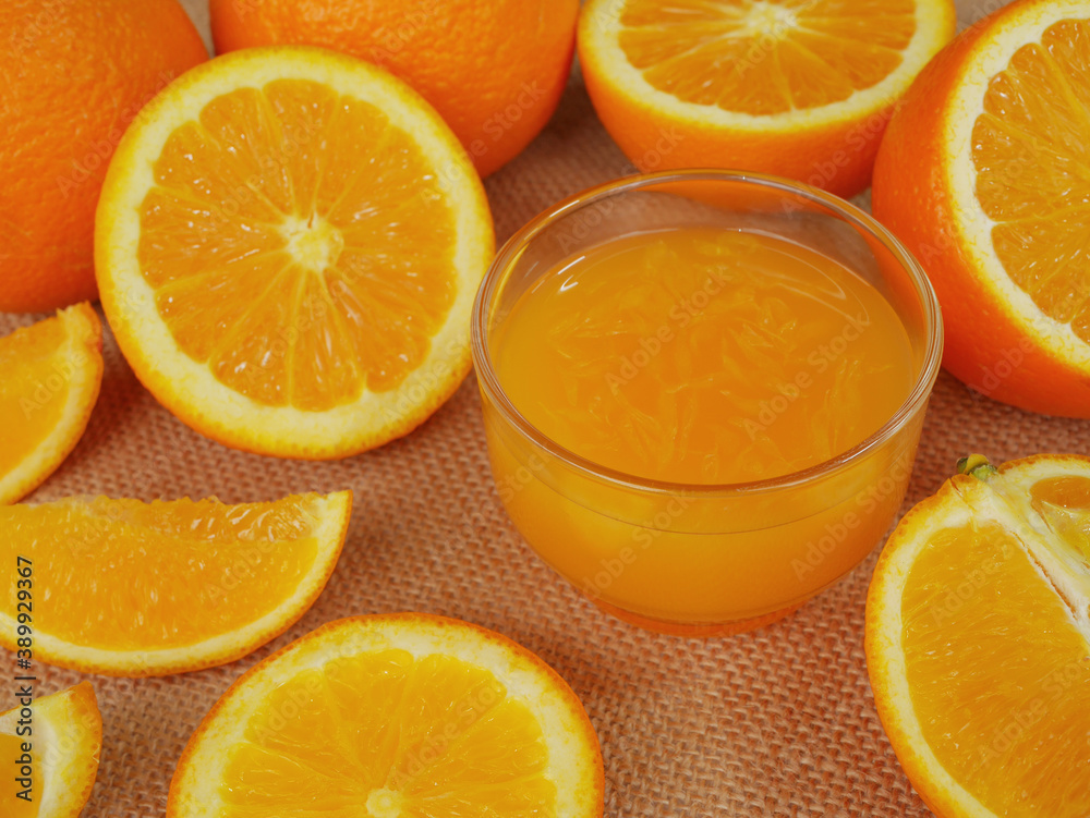 Fototapeta premium A cup of orange juice and many slided oranges on cutting board
