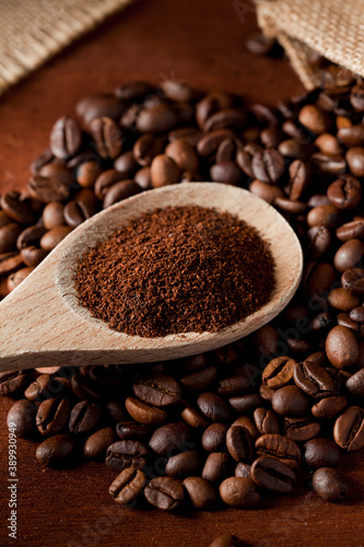 coffee powder (ground), on wooden spoon, coffee beans, with raffia cloth bag, brown background