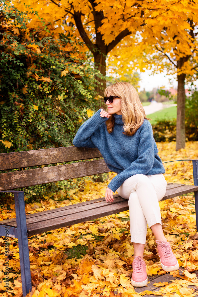 Happy woman enjoy fall weather while relaxing on the bench in the park Happy woman enjoy fall weather while relaxing on the bench in the park