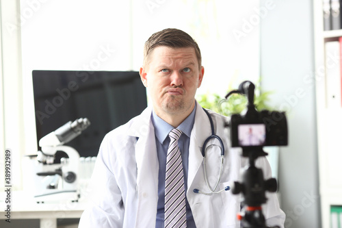 Portrait of thoughtful doctor recording video in video-blog. Popular blogger speaking to followers about work in laboratory. Blogging and vlog concept