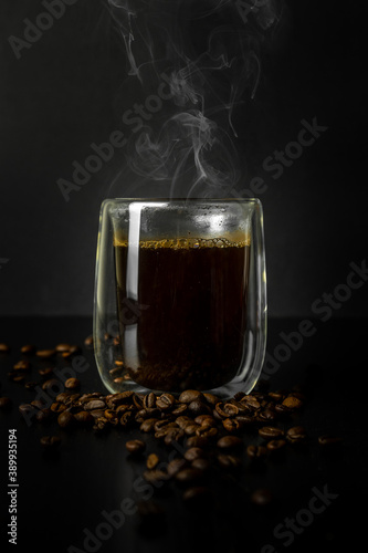 Freshly brewed steaming coffee in a glass Cup. Black background. Close up