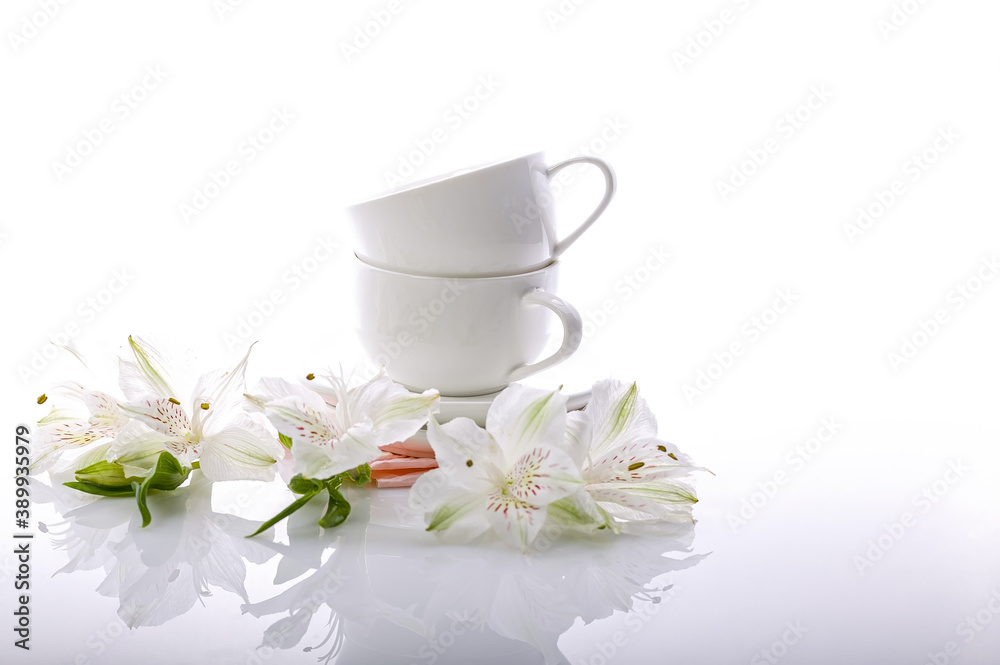 Two coffee white cups and exquisite flowers on a glossy background. Alstrameria. Still life Two coffee white cups and exquisite flowers on a glossy background. Alstrameria. Still life