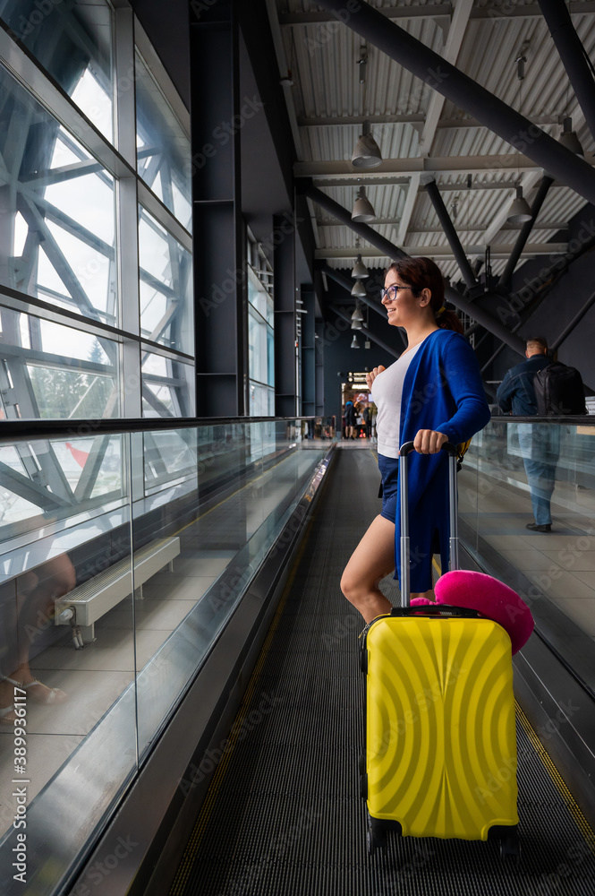 custom made wallpaper toronto digitalCaucasian woman on a horizontal escalator with a suitcase at the airport. A girl with pink luggage rides on a moving sidewalk