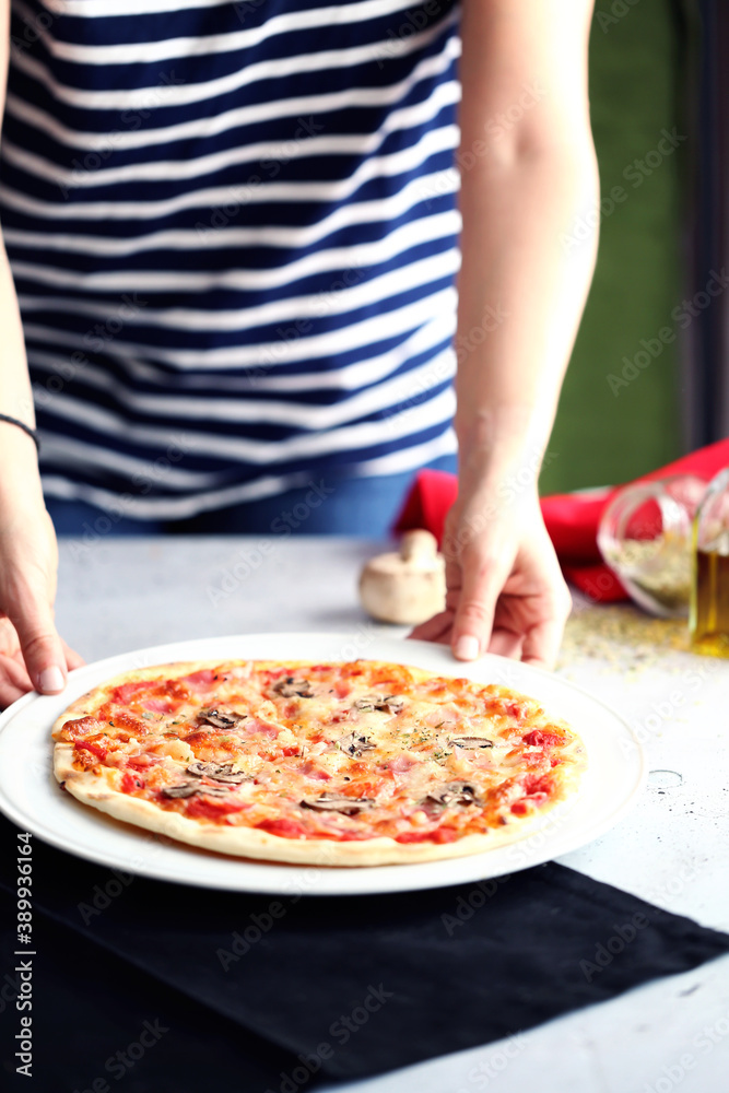 Person in striped shirt serves a pizza at the table.