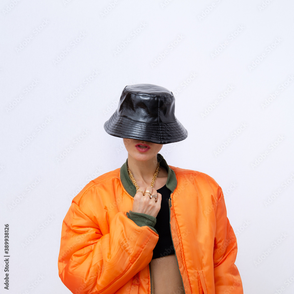 Girl in fashion street outfit. Trendy orange bomber jacket and stylish black hat. Fall winter seasons Style in details Photo | Adobe Stock