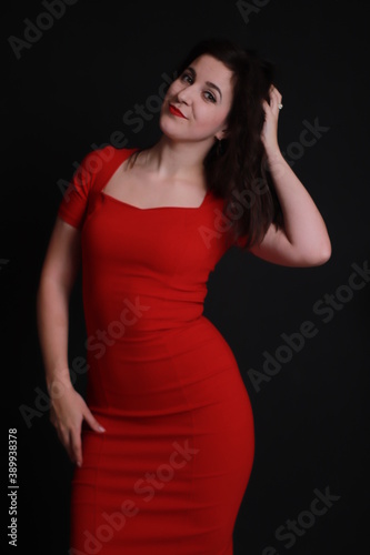 sexy attractive brunette in red skinny dress isolated on black background. studio shoot. emotional actress. . 