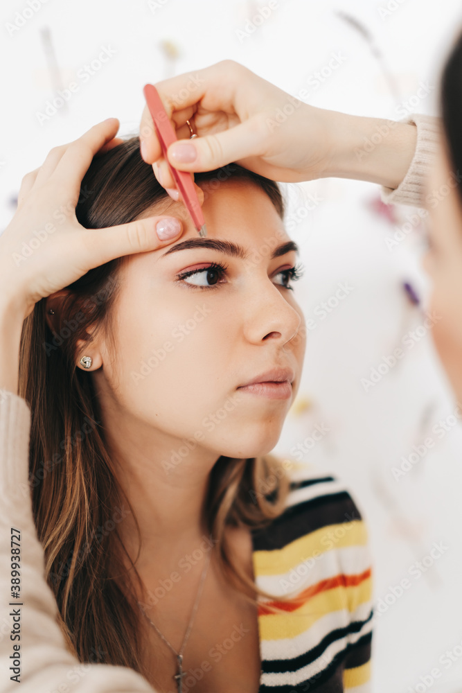 Fototapeta premium Eyebrow shaping procedure, make-up master uses tweezers to shape the eyebrows.