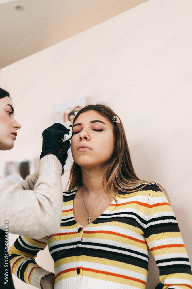 Eyebrow shaping procedure, make-up master uses brush to shape the eyebrows.