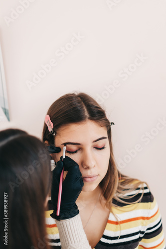 Eyebrow shaping procedure, make-up master uses brush to shape the eyebrows.