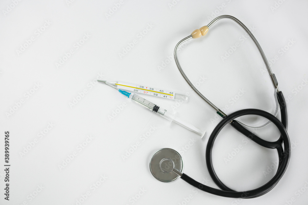 Stethoscope, syringe and thermometer on a white background. Selective focus, copy space. View from above. Cardiology concept Stethoscope, syringe and thermometer on a white background. Selective focus, copy space. View from above. Cardiology concept