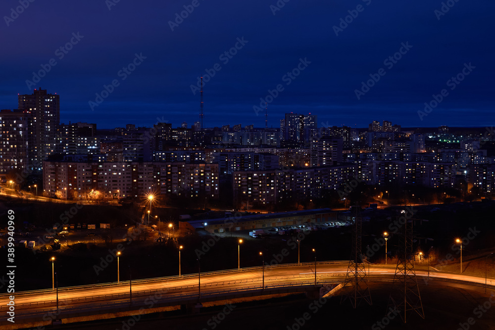 night cityscape with illuminated road in the foreground and residential areas in the background