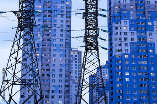 power line supports against the background of multi-storey residential buildings in the evening illumination