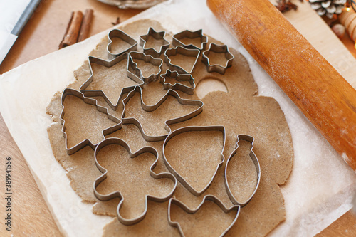 Raw gingerbread dough with festive metal cutters, wooden rolling pin, decorations on rustic table