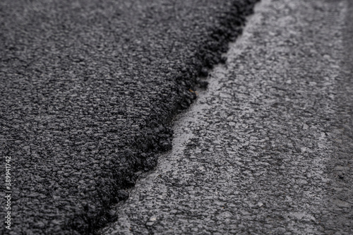 A large layer of fresh hot asphalt. Layer of asphalt raw material in a shallow depth of field. Rollers rollin fresh hot asphalt on the new road. Road construction. Construction of a new road.