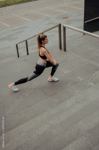 A young Caucasian girl, trains on the street, in sportswear, in the city.