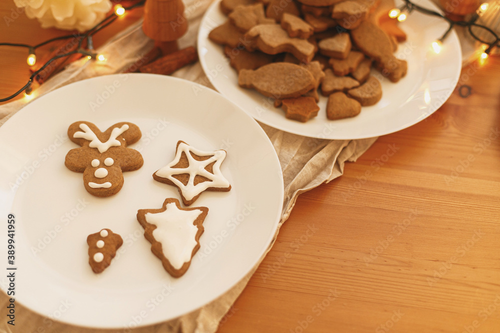 Gingerbread cookies with icing on wooden table with festive lights. Christmas tradition Gingerbread cookies with icing on wooden table with festive lights. Christmas tradition