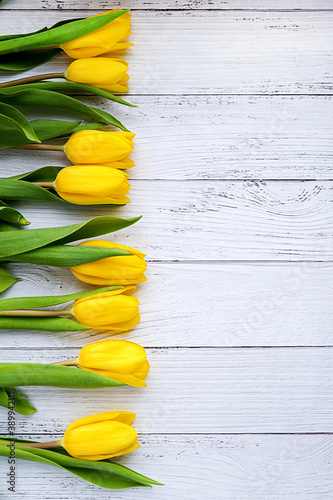 Yellow tulips flowers on white wooden background. Waiting for spring. HPlace for text.