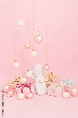 White angel with christmas ornaments over pink background. Minimal picture for winter holidays