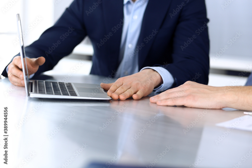 Business people using laptop computer while working together at the desk in modern office. Unknown businessman or male entrepreneur with colleague at workplace. Teamwork and partnership concept Business people using laptop computer while working together at the desk in modern office. Unknown businessman or male entrepreneur with colleague at workplace. Teamwork and partnership concept