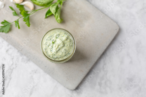 Obraz na plátne Homemade Green Goddess Dressing in a Jar on a Cement Cutting Board on White Marb