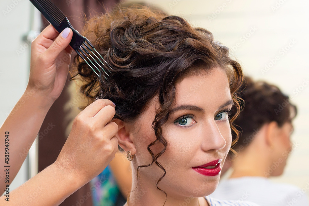 Fototapeta premium young woman in a beauty salon. Hairdresser makes hairstyle