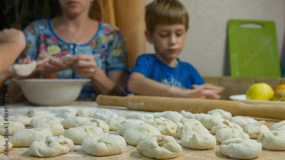 A woman with children are cooking meat pies in the kitchen A woman with children are cooking meat pies in the kitchen