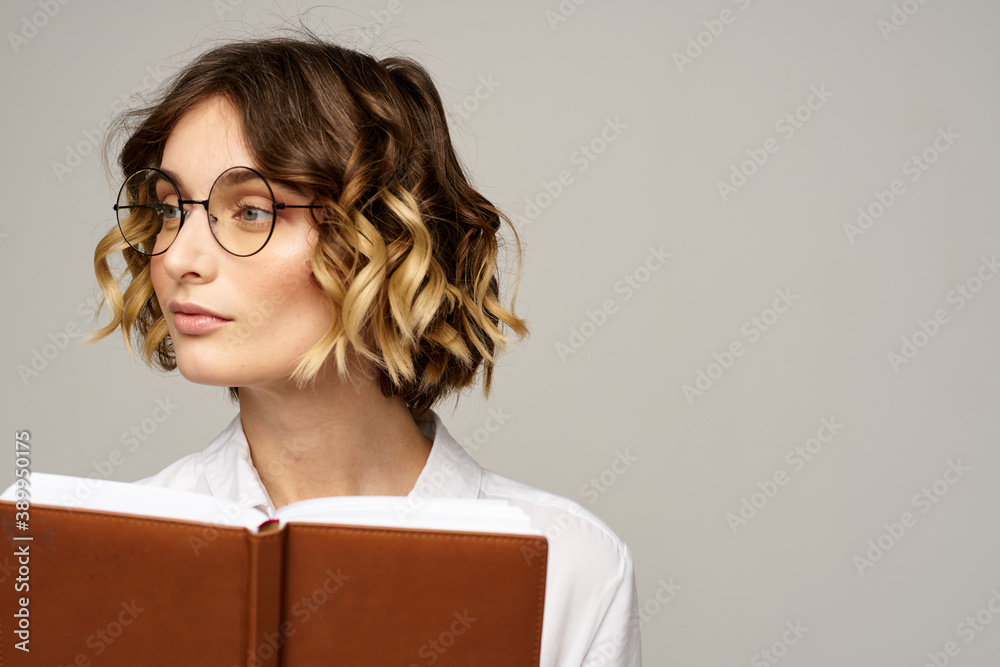 Business woman with notepad and glasses on a light background hairstyle success emotions Business woman with notepad and glasses on a light background hairstyle success emotions