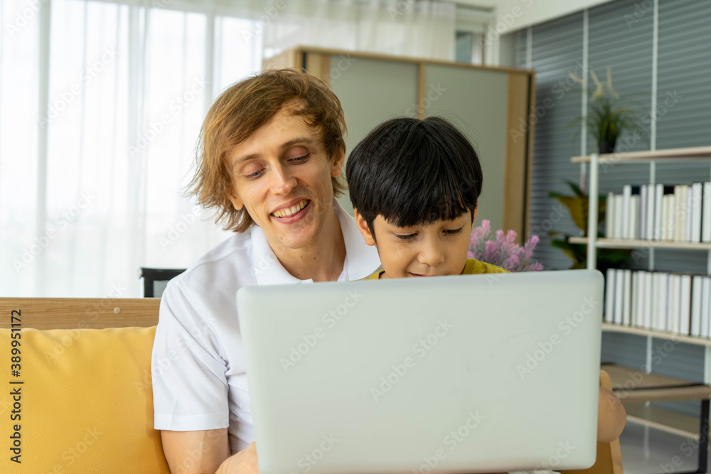 Young caucasian businessman and father working from home with notebook computer and taking care of little son in living room. Social distancing new normal concept. Young caucasian businessman and father working from home with notebook computer and taking care of little son in living room. Social distancing new normal concept.