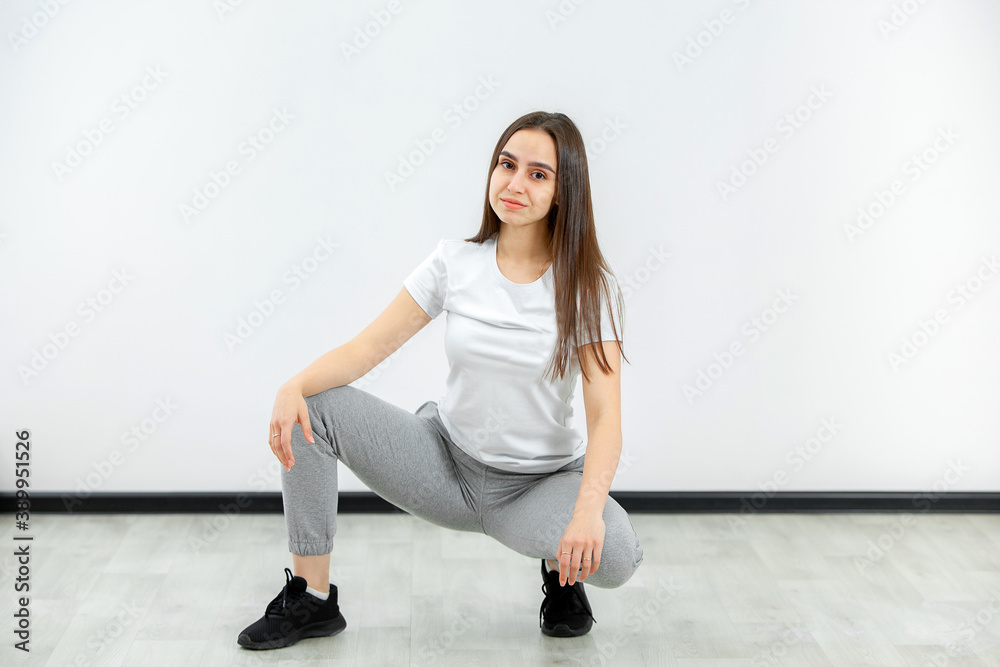 Stretch. Sporty woman stretching her body warming up on a white background. Full length portrait of sporty girl, fitness model in sportswear doing warm-up in studio Stretch. Sporty woman stretching her body warming up on a white background. Full length portrait of sporty girl, fitness model in sportswear doing warm-up in studio