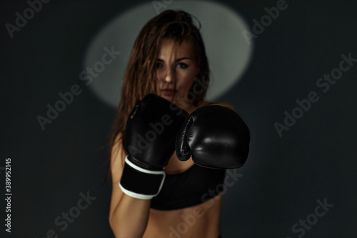 fashion photo of gorgeous sporty woman in boxing gloves punching on studio background. focus on glove