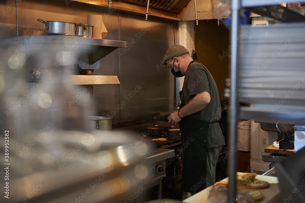 Middle aged man working in fast food industry wearing a facial mask to protect from covid-19. Middle aged man working in fast food industry wearing a facial mask to protect from covid-19.