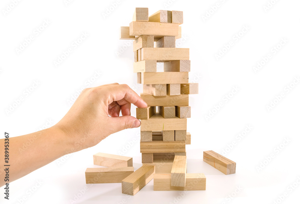 Tower of wooden blocks and human hands take one block. planning, risk and strategy in business. at the risk of taking a wooden block from the tower. Tower of wooden blocks and human hands take one block. planning, risk and strategy in business. at the risk of taking a wooden block from the tower.