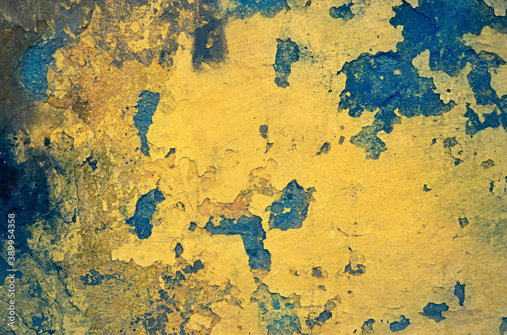 Yellow grunge wall with paint peeling off. Toned image.