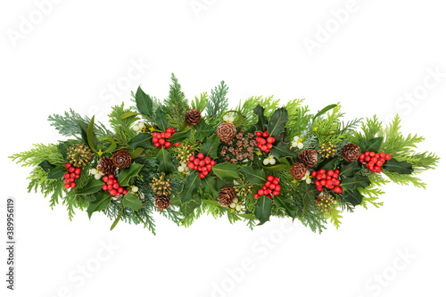 Decorative winter  Christmas   New Year floral composition with holly  ivy  mistletoe  cedar cypress fir leaves   pine cones on white background. Natural decoration for the holiday season. Flat lay.