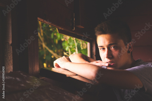 Young adult looking through the window of a wooden cabin. photo