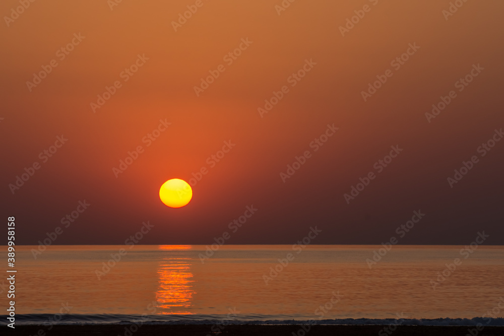 warm orange sun at the horizon from the sea and waves