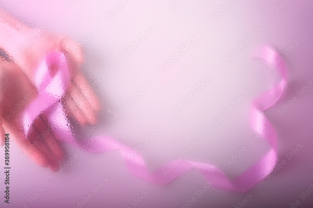 Close up of female hand holding satin pink ribbon awareness copy space. Women's health care and medical concept.